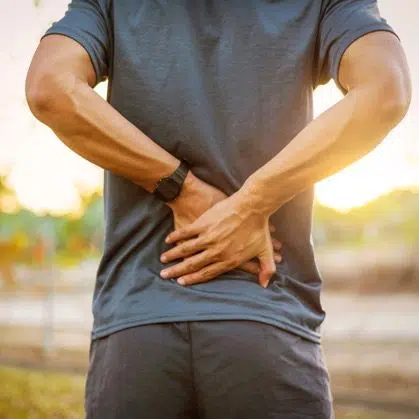 Young man having a back pain during outdoor exercise