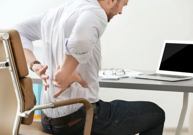 Young man suffering from Degenerative Disc Disease while at work