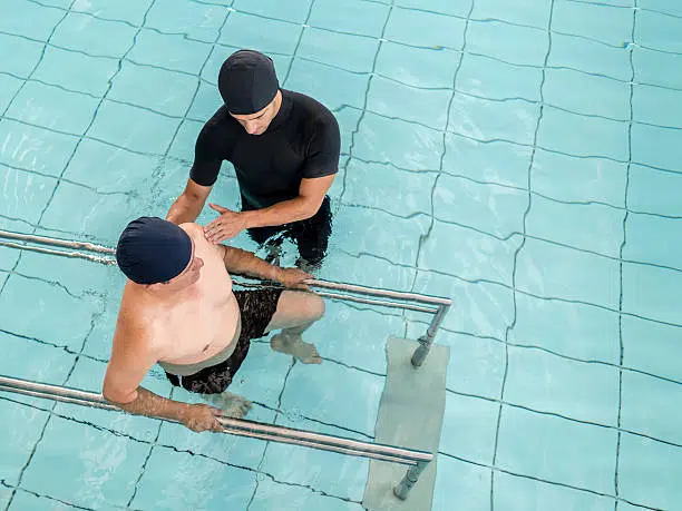 Man is doing water therapy with his therapist to strengthen the back muscles