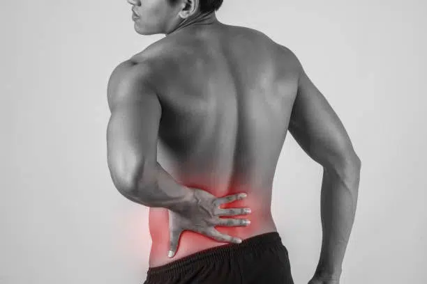 Man suffering from severe lower back pain - grayscale with pain area in red