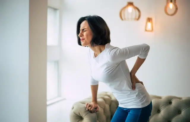 Adult woman holding her back because of severe pain caused by failed surgery